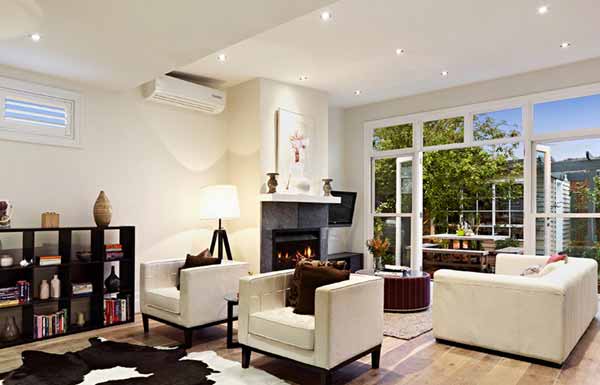 Split system air conditioner in a bright Melbourne living room with fireplace and garden doors
