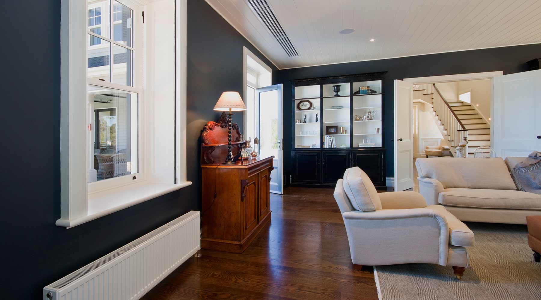 Living Room in Callanans Road, Red Hill with VRV mini ducted bulkhead air conditioning, Linear slot diffusers, Hydronic heating with ribbed radiant panels
